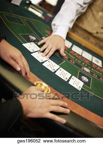 Stock Image - Mid section view of a casino worker dealing with playing cards on a gambling table. Fotosearch