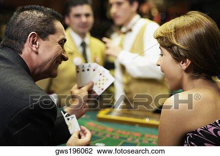 Rear view of a mature man showing playing cards to a young woman in a casino View Large Photo Image Stock Image - Rear view of a mature man showing playing cards to a young woman in a casino. Fotosearch