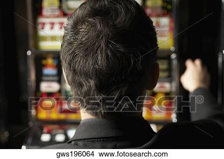 Rear view of a mid adult man playing on a slot machine View Large Photo Image Picture - Rear view of a mid adult man playing on a slot machine. Fotosearch