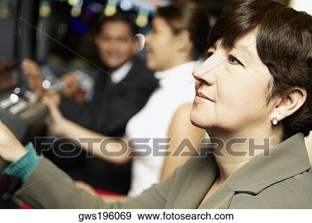 Stock Photo - Side profile of a mature woman looking at a slot machine. Fotosearch
