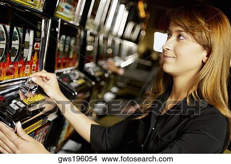 Side profile of a young woman using a slot machine in a casino View Large Photo Image Picture - Side profile of a young woman using a slot machine in a casino. Fotosearch
