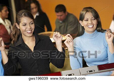 Stock Photo - Teenage girl with a young woman playing on slot machines. Fotosearch