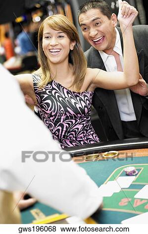 Young woman cheering at a gambling table with a mature man standing beside her in a casino View Large Photo Image Stock Photo - Young woman cheering at a gambling table with a mature man standing beside her in a casino. Fotosearch