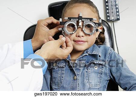 Stock Image - Close-up of a doctor's hand examining a girl's eye. Fotosearch