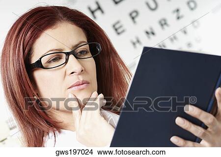 Close-up of a female optometrist reading a report View Large Photo Image Picture - Close-up of a female optometrist reading a report. Fotosearch