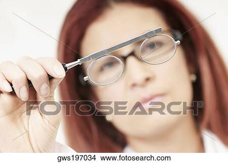 Close-up of a female optometrist holding an eye test equipment View Large Photo Image Picture - Close-up of a female optometrist holding an eye test equipment. Fotosearch