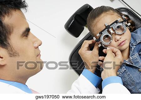 Stock Image - Close-up of a male doctor examining a girl's eye. Fotosearch