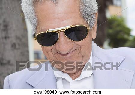 Stock Image - Close-up of a senior man wearing sunglasses and smiling. Fotosearch