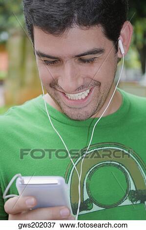 Close-up of a young man listening to an MP3 player View Large Photo Image Stock Photo - Close-up of a young man listening to an MP3 player. Fotosearch