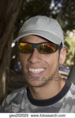 Close-up of a young man wearing sunglasses and smiling View Large Photo Image Stock Photography - Close-up of a young man wearing sunglasses and smiling. Fotosearch