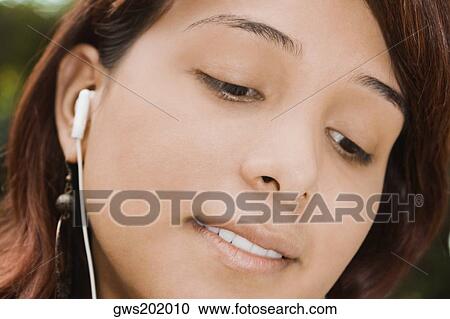 Stock Image - Close-up of a young woman listening to music. Fotosearch