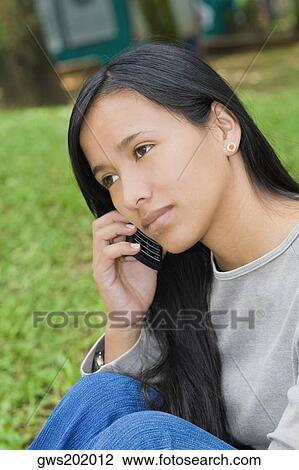 Close-up of a young woman talking on a mobile phone View Large Photo Image Stock Image - Close-up of a young woman talking on a mobile phone. Fotosearch