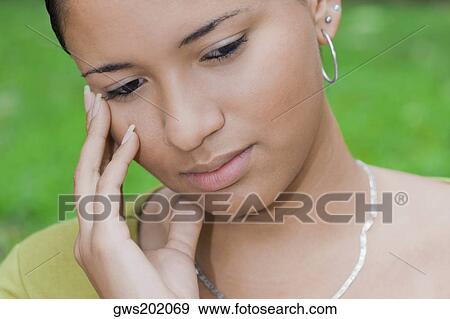Close-up of a young woman touching her face View Large Photo Image Stock Photo - Close-up of a young woman touching her face. Fotosearch