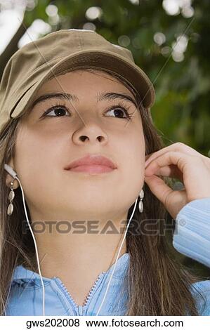 Stock Photo - Close-up of a young woman wearing headphones and looking up. Fotosearch