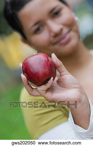 Portrait of a young woman holding an apple View Large Photo Image Stock Image - Portrait of a young woman holding an apple. Fotosearch