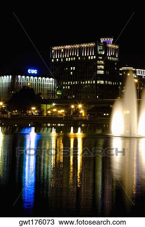 Stock Image - Fountains lit up at night in front of buildings, Orlando, Florida, USA. Fotosearch