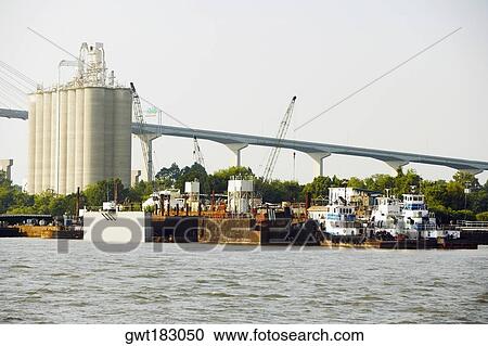 Stock Image - Commercial dock with a bridge in the background, Savannah, Georgia, USA. Fotosearch