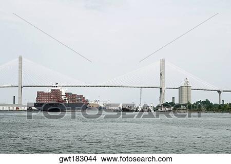 Container ship in a river with a suspension bridge in the background, Talmadge Bridge, Savannah River, Savannah, Georgia, USA View Large Photo Image Picture - Container ship in a river with a suspension bridge in the background, Talmadge Bridge, Savannah River, Savannah, Georgia, USA. Fotosearch