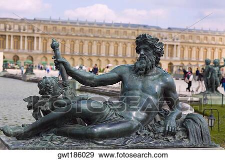 Close-up of a statue with a palace in the background, Statue Of Neptune, Palace of Versailles, Versailles, France View Large Photo Image Stock Photo - Close-up of a statue with a palace in the background, Statue Of Neptune, Palace of Versailles, Versailles, France. Fotosearch