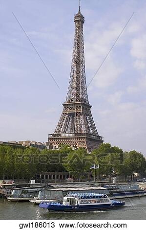 Stock Image - Tourboats moored in a river with a tower in background, River Seine, Eiffel Tower, Paris, France. Fotosearch