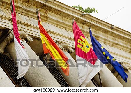 Stock Photo - Low angle view of four flags on a government building, Toledo, Spain. Fotosearch