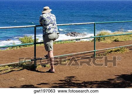 Rear view of a man leaning against a railing on the beach, Hookipa Beach, Maui, Hawaii Islands, USA View Large Photo Image Stock Image - Rear view of a man leaning against a railing on the beach, Hookipa Beach, Maui, Hawaii Islands, USA. Fotosearch