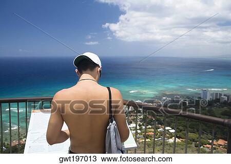Stock Image - Rear view of a man standing at an observation point, Diamond Head, Waikiki Beach, Honolulu, Oahu, Hawaii Islands, USA. Fotosearch