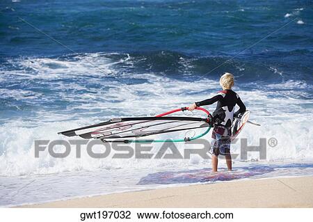 Rear view of a person holding a windsurfing board on the beach, Hookipa Beach Park, Maui, Hawaii Islands, USA View Large Photo Image Stock Image - Rear view of a person holding a windsurfing board on the beach, Hookipa Beach Park, Maui, Hawaii Islands, USA. Fotosearch