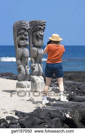 Rear view of a woman taking a photograph of tikies on the coast, Puuhonua O Honaunau National Historical Park, Kona Coast, Big Island, Hawaii Islands, USA View Large Photo Image Stock Image - Rear view of a woman taking a photograph of tikies on the coast, Puuhonua O Honaunau National Historical Park, Kona Coast, Big Island, Hawaii Islands, USA. Fotosearch