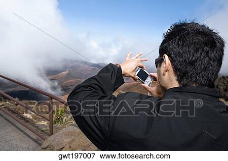 Rear view of a young man taking a photograph, Haleakala National Park, Maui, Hawaii Islands, USA View Large Photo Image Stock Photo - Rear view of a young man taking a photograph, Haleakala National Park, Maui, Hawaii Islands, USA. Fotosearch