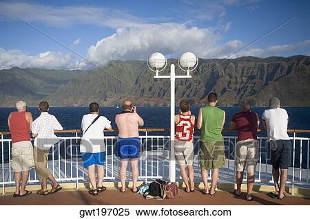Stock Photography - Rear view of tourists standing at observation point looking at a view, Na Pali Coast State Park, Kauai, Hawaii Islands, USA. Fotosearch