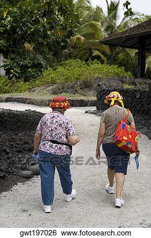 Rear view of two women walking on a walkway, Puuhonua O Honaunau National Historical Park, Kona Coast, Big Island, Hawaii Islands, USA View Large Photo Image Stock Photograph - Rear view of two women walking on a walkway, Puuhonua O Honaunau National Historical Park, Kona Coast, Big Island, Hawaii Islands, USA. Fotosearch