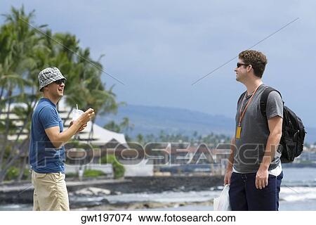 Two young men standing on the beach, Kona, Big Island, Hawaii Islands, USA View Large Photo Image Picture - Two young men standing on the beach, Kona, Big Island, Hawaii Islands, USA. Fotosearch