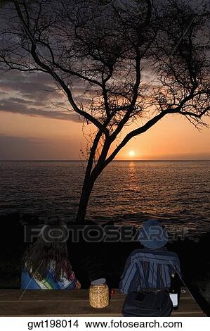 Man and a woman looking at sunset over the sea, Pakini Nui Wind Project, South Point, Big Island, Hawaii Islands, USA View Large Photo Image Picture - Man and a woman looking at sunset over the sea, Pakini Nui Wind Project, South Point, Big Island, Hawaii Islands, USA. Fotosearch