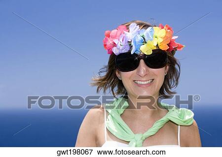 Stock Photo - Mid adult woman wearing flowers and smiling. Fotosearch