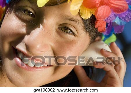 Portrait of a girl wearing flowers and listening to a conch shell View Large Photo Image Stock Image - Portrait of a girl wearing flowers and listening to a conch shell. Fotosearch