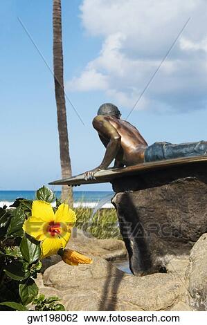 Stock Image - Statue of a man lying on front on the surfboard, Waikiki Beach, Honolulu, Oahu, Hawaii Islands, USA. Fotosearch