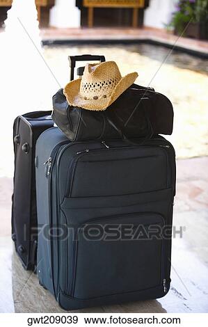 Stock Photo - Close-up of a hand bag and a straw hat on a suitcase at the poolside, Cancun, Mexico. Fotosearch