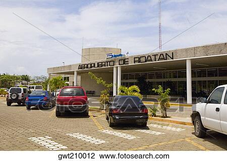 Stock Image - Cars parked in front of an airport entrance, Roatan, Bay Islands, Honduras. Fotosearch