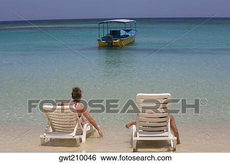 Tourists sitting on the beach chairs, West Bay Beach, Roatan, Bay Islands, Honduras View Large Photo Image Stock Photograph - Tourists sitting on the beach chairs, West Bay Beach, Roatan, Bay Islands, Honduras. Fotosearch