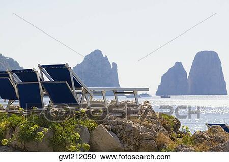 Deck chairs on a rock, Faraglioni Rocks, Capri, Campania, Italy View Large Photo Image Stock Image - Deck chairs on a rock, Faraglioni Rocks, Capri, Campania, Italy. Fotosearch