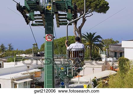 Rear view of a man sitting in an overhead cable car, Capri, Campania, Italy View Large Photo Image Stock Photograph - Rear view of a man sitting in an overhead cable car, Capri, Campania, Italy. Fotosearch