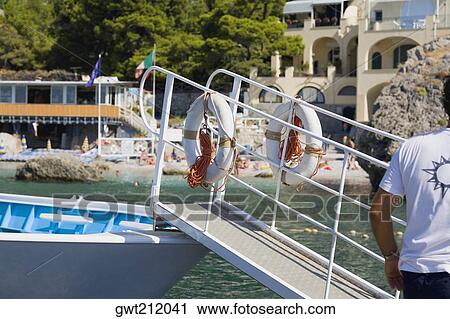 Rear view of a man standing near a boat, Capri, Campania, Italy View Large Photo Image Stock Image - Rear view of a man standing near a boat, Capri, Campania, Italy. Fotosearch