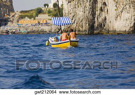 Picture - Rear view of two people in a boat, Capri, Campania, Italy. Fotosearch