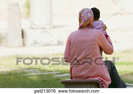 Rear view of a woman picking up her baby, Ephesus, Turkey View Large Photo Image Stock Photograph - Rear view of a woman picking up her baby, Ephesus, Turkey. Fotosearch