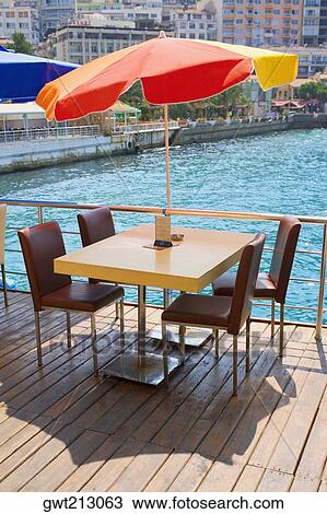 Stock Image - Table with four chairs under a patio umbrella in a restaurant, Ephesus, Turkey. Fotosearch