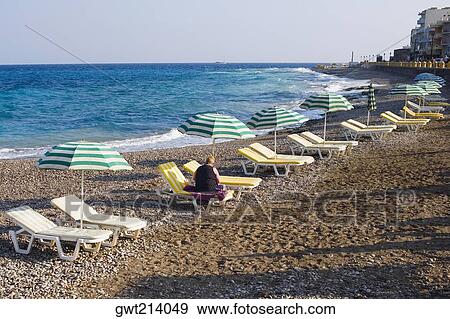 Stock Photo - Beach umbrellas and lounge chairs on the beach, Lindos, Rhodes, Dodecanese Islands, Greece. Fotosearch