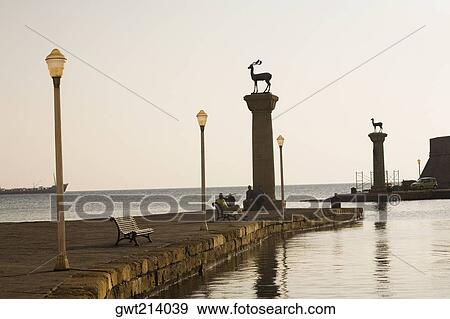 Stock Photo - Monuments in the sea, Mandraki Harbor, Rhodes, Dodecanese Islands, Greece. Fotosearch