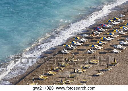 Stock Image - High angle view of beach umbrellas and lounge chairs on the beach, Greece. Fotosearch