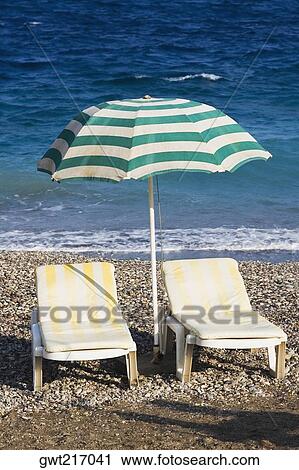 Two lounge chairs under a beach umbrella on the beach, Greece View Large Photo Image Stock Image - Two lounge chairs under a beach umbrella on the beach, Greece. Fotosearch